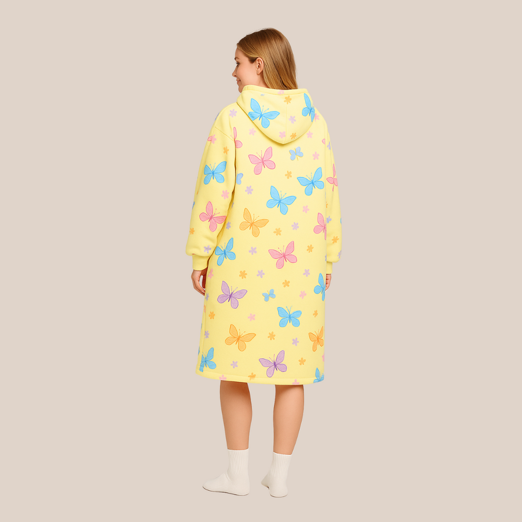 Back view of a woman wearing the Butterfly Dream hoodie blanket in yellow fleece with pastel butterflies.