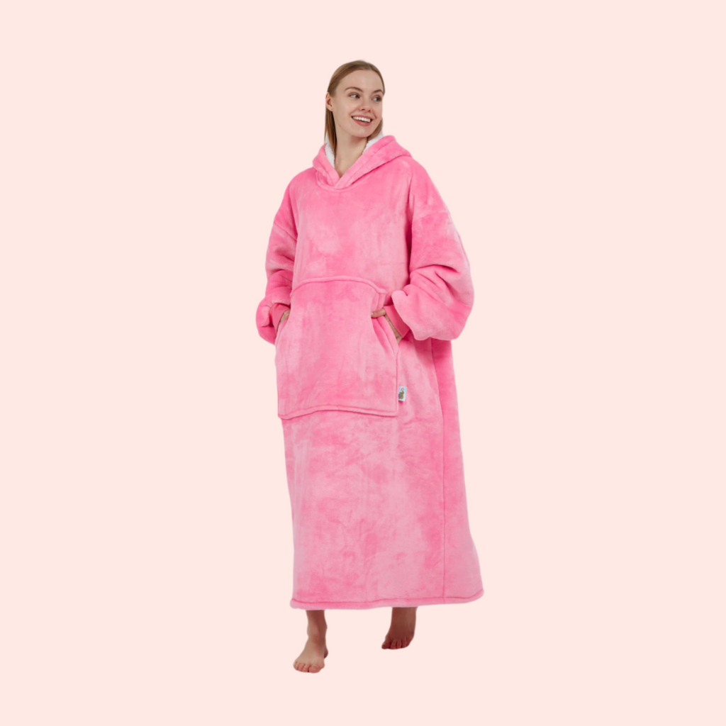 Side view of model walking in plush pink hoodie blanket with kangaroo pocket.